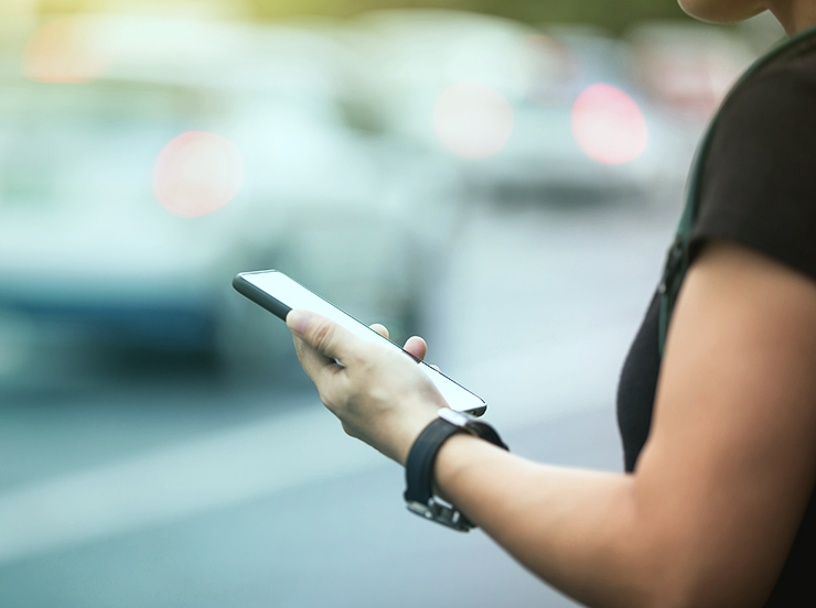 Woman hands using smartphone at city street side,checking the ride-hailing apps